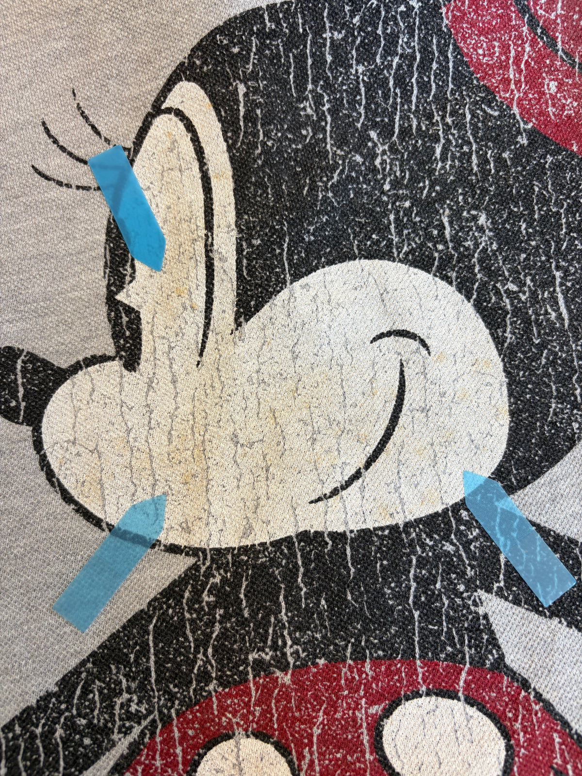 Close-up view of a Disney Minnie Mouse graphic polo shirt print showing multiple yellow stain defects marked with blue stickers.