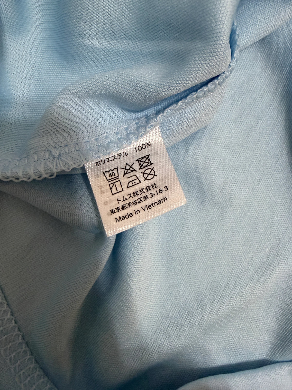 Close-up of a blue fabric with a label indicating 100% polyester and 'Made in Vietnam'.