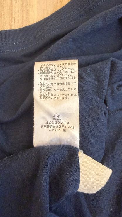Close-up view of the white Japanese care instruction tag stitched inside a navy Peanuts Snoopy t-shirt showing washing instructions and Grace Co. manufacturer details