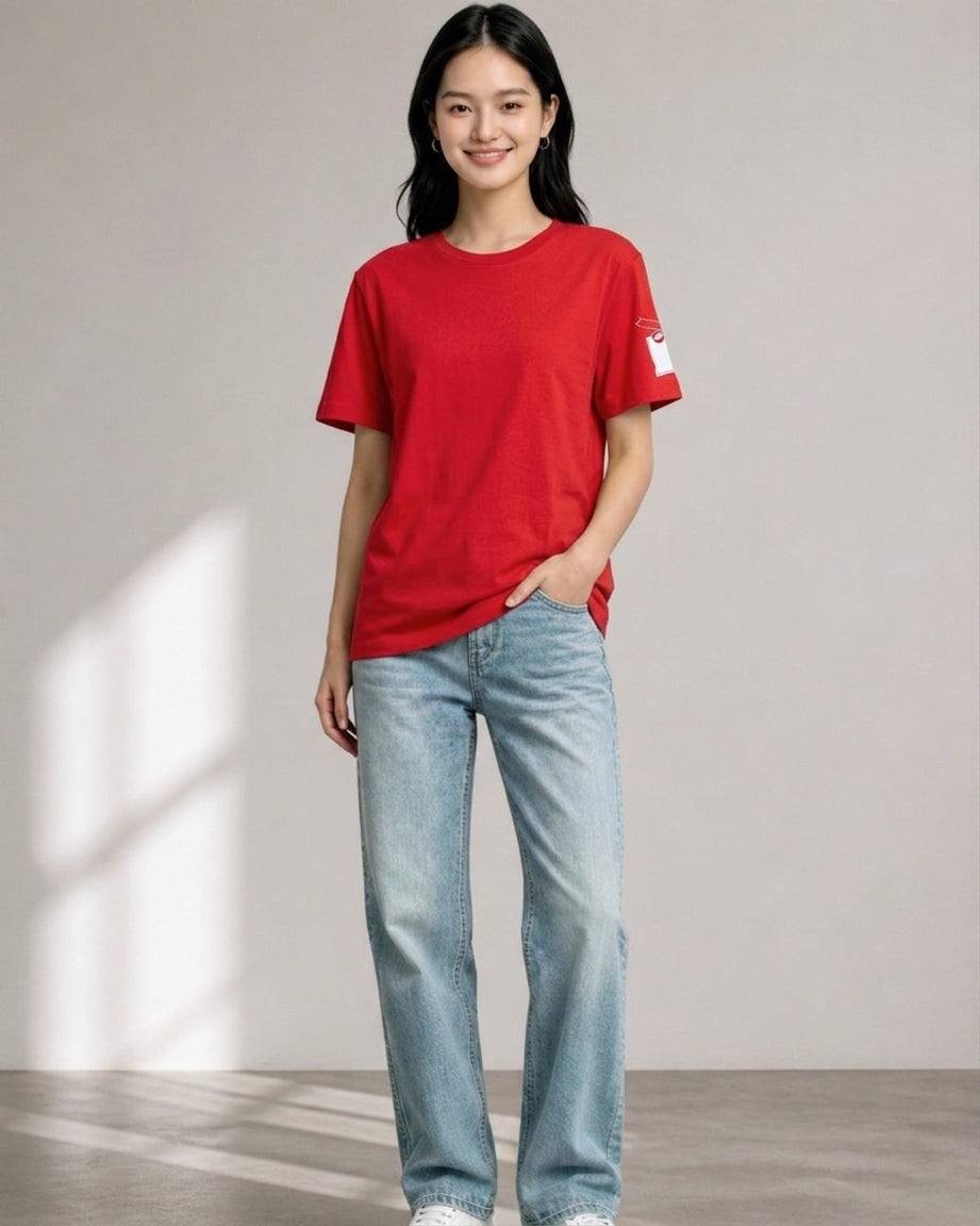 Woman standing in full view wearing a solid red Starbucks holiday t-shirt with sleeve tag print and light wash blue jeans