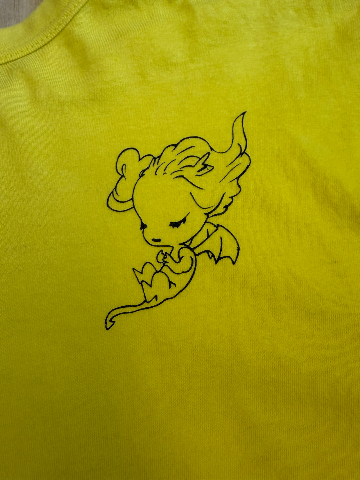 Back view of a yellow Yoshitaka Amano x 24 Hour Television 37th charity t-shirt featuring a black line art illustration of a sleeping winged fantasy character